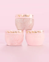 Tři růžové nádobky P.Louise Hop Into Self-Care Pink Marshmallow obsahující koupelové soli, tělový peeling a tělové máslo se zlatým textem na růžovém pozadí