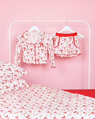 Sett med rosa og hvitstripete jenter P.Louise julesløyfe pyjamasshorts på kleshengere i et rosa soverom med matchende sengetøy 