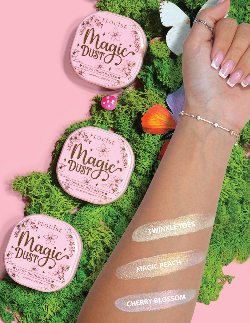 Tri kompaktna rasuta highlightera s oznakom Magic Dust u nijansama Twinkle Toes, Magic Peach i Cherry Blossom, prikazana na ruci s cvjetnom pozadinom.