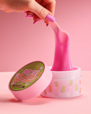 Tub of P. Louise Peel The Love Peel Off Facial Mask being pulled out of tub with an applicator on a pink background
