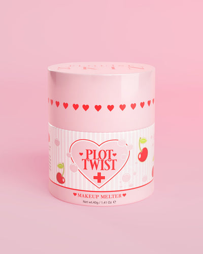Un contenitore rosa di P.Louise Plot Twist Makeup Melting Cleansing Balm con disegni di cuori e ciliegie sull'etichetta su uno sfondo rosa