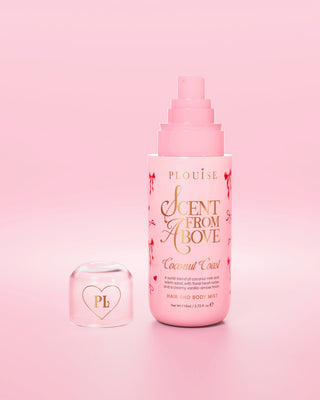 Bottiglia rosa di spray per capelli e corpo "Scent from Above" con disegni di fiocchi rossi sulla bottiglia e tappo staccato