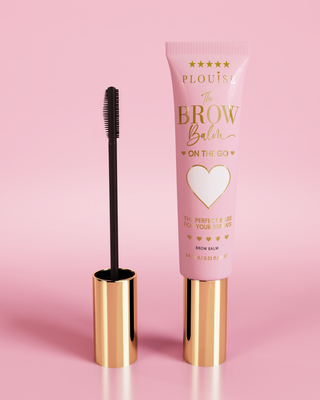 Produit P.Louise Fluffy Soap Brow Balm Instant Fix dans un tube rose avec un capuchon doré, accompagné d'un pinceau à sourcils noir, présenté sur fond rose.