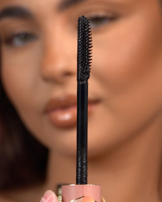 Close-up of a P.Louise Tearproof waterproof mascara wand held in front of a blurred face