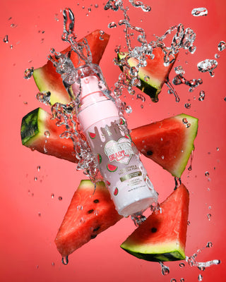 Rosa flaske med vannmelondesign omgitt av vannmelonskiver og vanndråper på rød bakgrunn