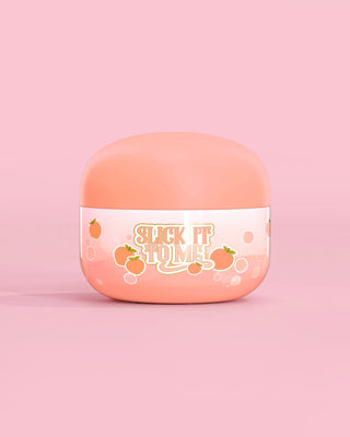 Krukke med P. Louise Slick It To Me Peach Melting Body Balm med rosa bakgrunn