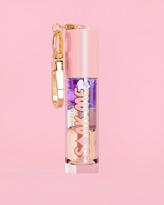 P. Louise Soak Me Lip Oil met kleurrijke gelaagde olie in een roze tube met gouden sluiting op een roze achtergrond