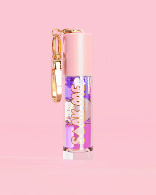 P. Louise Soak Me Lip Oil met kleurrijke gelaagde olie in een roze tube met gouden sluiting op een roze achtergrond
