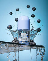 Bottiglia di P. Louise Clear The Air Blueberry Gel Cleanserl circondata da mirtilli e spruzzi d'acqua su uno sfondo blu