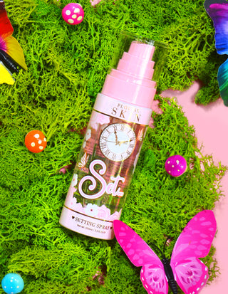 En flaske P. Louise Ready Set Slay Long Lasting Setting Spray omgivet af dekorative elementer, herunder farverigt imiteret mos, sommerfugle og svampe.