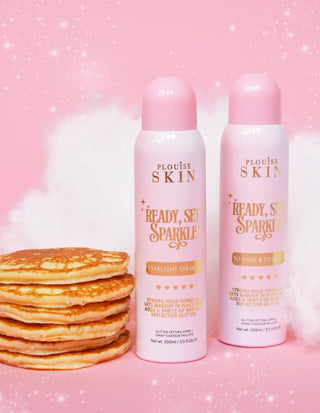 Två aerosolburkar P. Louise Ready Set Sparkle Glitter Setting Spray med en bunt pannkakor och en rosa bakgrund med gnistrar