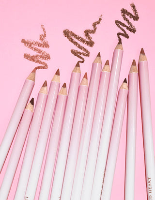 En bild av flera P.Louise Ultimate Definition Sharpenable Lip Liners grupperade tillsammans som visar någon produkt ritad ovanför dem på en rosa bakgrund