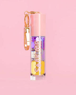 P. Louise Soak Me Lip Oil met kleurrijke gelaagde olie in een roze tube met gouden sluiting op een roze achtergrond