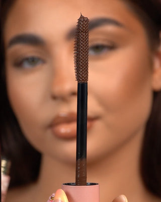 Close-up of a P.Louise Tearproof waterproof mascara wand held in front of a blurred face